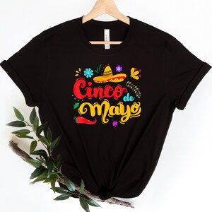 May include: Black t-shirt with a colorful graphic design that says "Cinco de Mayo" with a sombrero and chili pepper.