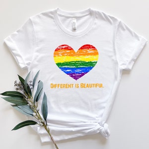 May include: White t-shirt with a rainbow heart and the text "Different is Beautiful" in orange.