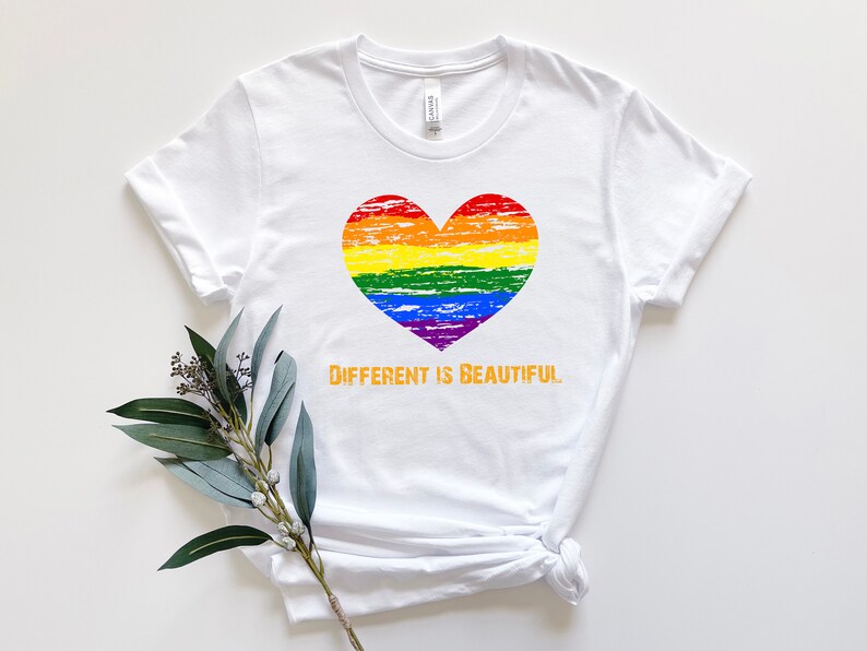 May include: White t-shirt with a rainbow heart and the text "Different is Beautiful" in orange.