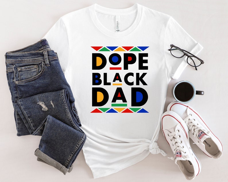 K&ouml;nnte beinhalten: Wei&szlig;es T-Shirt mit einem grafischen Design, das "Dope Black Dad" in schwarzen und gelben Buchstaben mit einem bunten geometrischen Muster um den Text herum sagt.