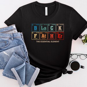 Puede incluir: Camiseta negra con un gr&aacute;fico de la tabla peri&oacute;dica de los elementos que deletrea "BLACK" y "FATHER" con el texto "The Essential Element" debajo.
