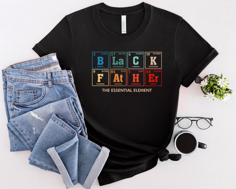 Puede incluir: Camiseta negra con un gr&aacute;fico de la tabla peri&oacute;dica de los elementos que deletrea "BLACK" y "FATHER" con el texto "The Essential Element" debajo.