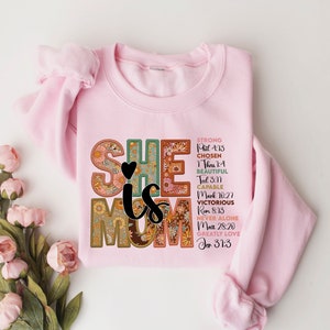 May include: Pink sweatshirt with a floral design that says "She is Mom" with bible verses listed below.