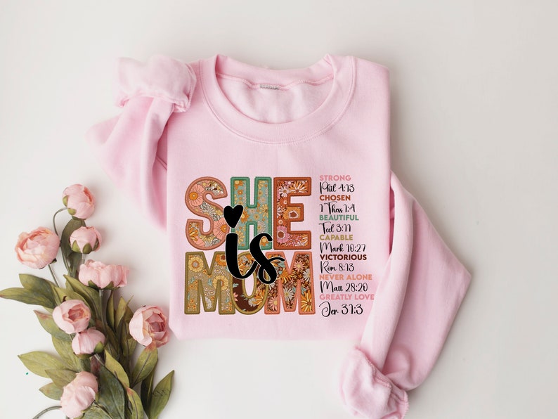 May include: Pink sweatshirt with a floral design that says "She is Mom" with bible verses listed below.