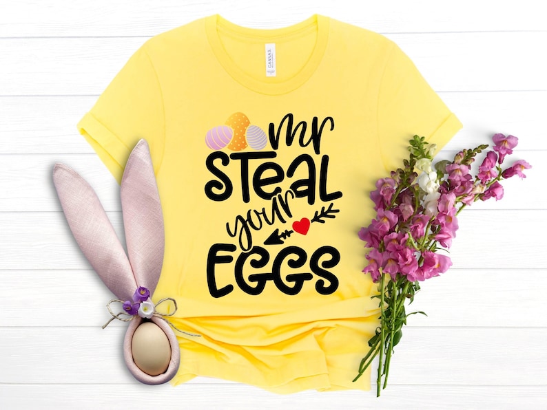 May include: Yellow t-shirt with a black graphic that says "Mr Steal Your Eggs" with a red heart and a small arrow. The graphic also includes three colourful Easter eggs.