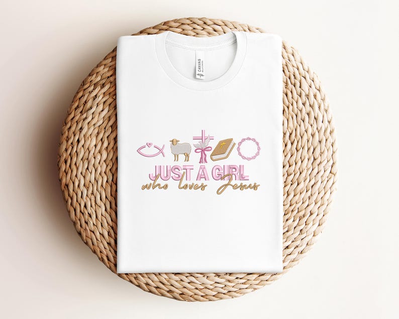 May include: White t-shirt with a pink and gold design that says "Just a girl who loves Jesus". The design includes a fish, a lamb, a cross, a bible, and a wreath.