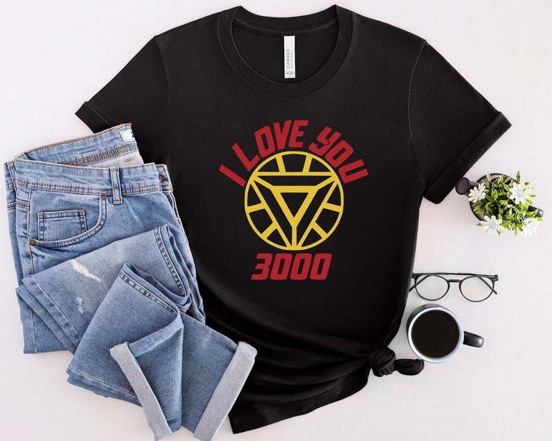 Puede incluir: Camiseta negra con un logotipo de Iron Man rojo y amarillo y el texto "I Love You 3000".