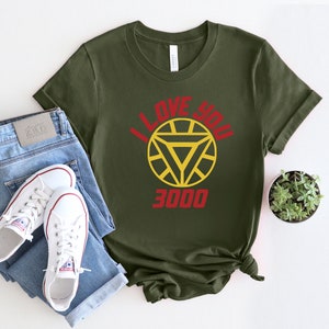 Puede incluir: Una camiseta verde con un logotipo de Iron Man rojo y amarillo y el texto "I love you 3000".