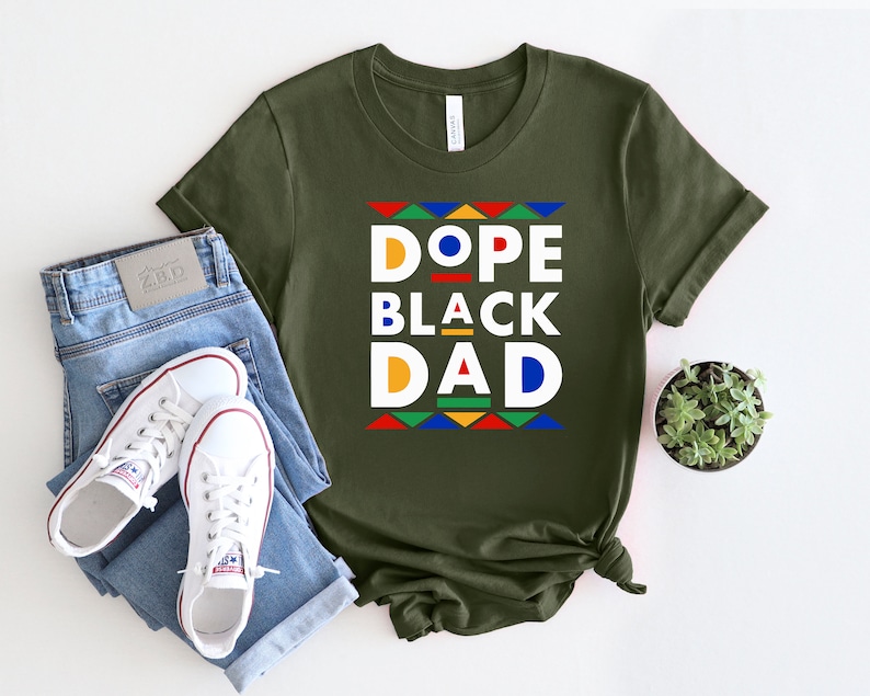 K&ouml;nnte beinhalten: Ein gr&uuml;nes T-Shirt mit einer wei&szlig;en Grafik, auf der "Dope Black Dad" im Retro-Stil mit bunten geometrischen Formen steht.