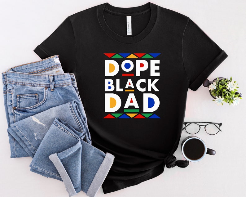 K&ouml;nnte beinhalten: Schwarzes T-Shirt mit einer bunten Grafik, auf der im Retro-Stil "Dope Black Dad" steht.