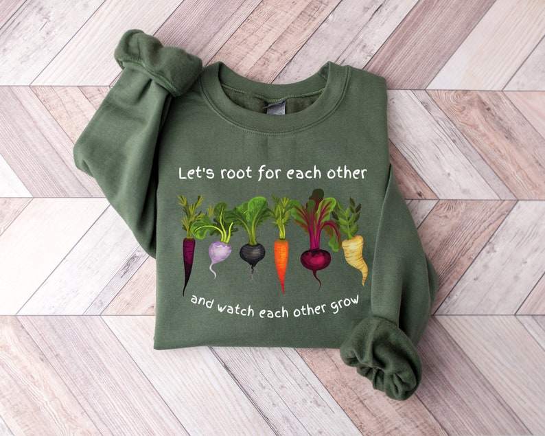 May include: A green sweatshirt with a white graphic of vegetables and the text "Let's root for each other and watch each other grow".