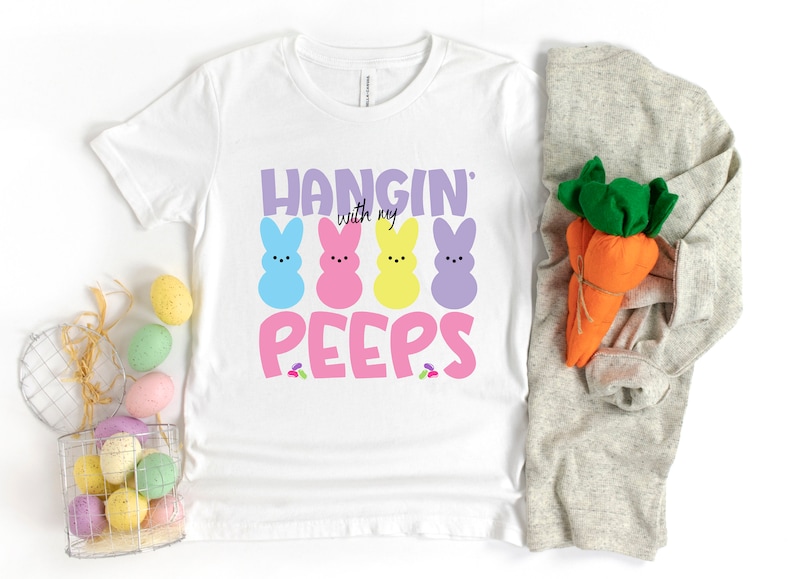 May include: White t-shirt with a pink, yellow, blue, and purple peep design and the text "Hangin' with my peeps".