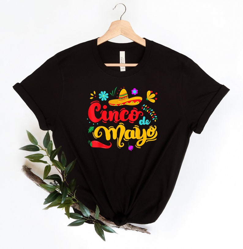 May include: Black t-shirt with a colorful graphic design that says "Cinco de Mayo" with a sombrero and chili pepper.