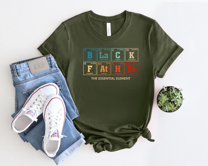 Puede incluir: Una camiseta verde con un gr&aacute;fico de la tabla peri&oacute;dica de los elementos que deletrea "BLACK" y "F*CKER" con el texto "THE ESSENTIAL ELEMENT" debajo.