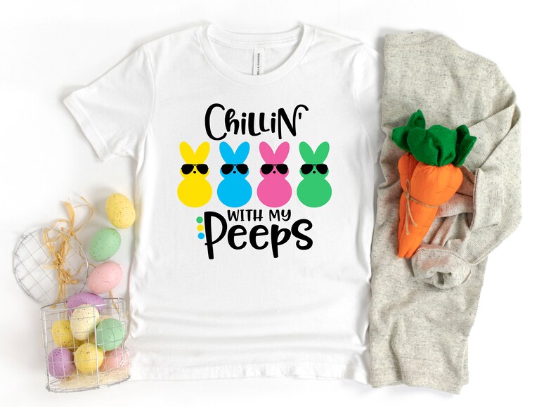 May include: White t-shirt with the text "Chillin' with my Peeps" and four cartoon Peeps wearing sunglasses. The Peeps are yellow, blue, pink, and green.