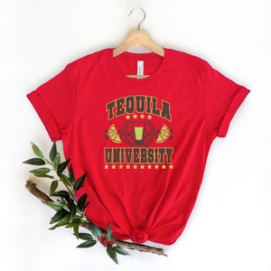 May include: Red t-shirt with a graphic design that says "Tequila University" with a shot glass and lime wedges.