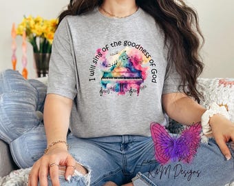 May include: A gray t-shirt with a watercolor design of a piano with musical notes and the text "I will sing of the goodness of God".