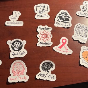 May include: A selection of white stickers featuring black and red designs and text. The stickers depict medical imagery, anatomical drawings, and phrases such as "Cat Scan", "Rad Lyfe", and "Donut of Truth Operator."