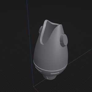 May include: A gray, 3D-rendered object resembling a mask or respirator. It has a rounded, bulbous shape with a curved top and two circular side features. The design includes horizontal lines and a cylindrical base.
