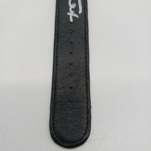 May include: Close-up of a black leather watch strap with white stitching and the word "Left" written on it.