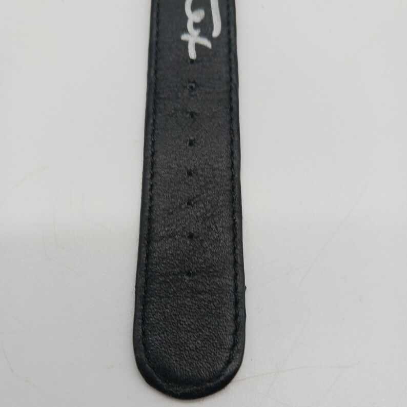 May include: Close-up of a black leather watch strap with white stitching and the word "Left" written on it.