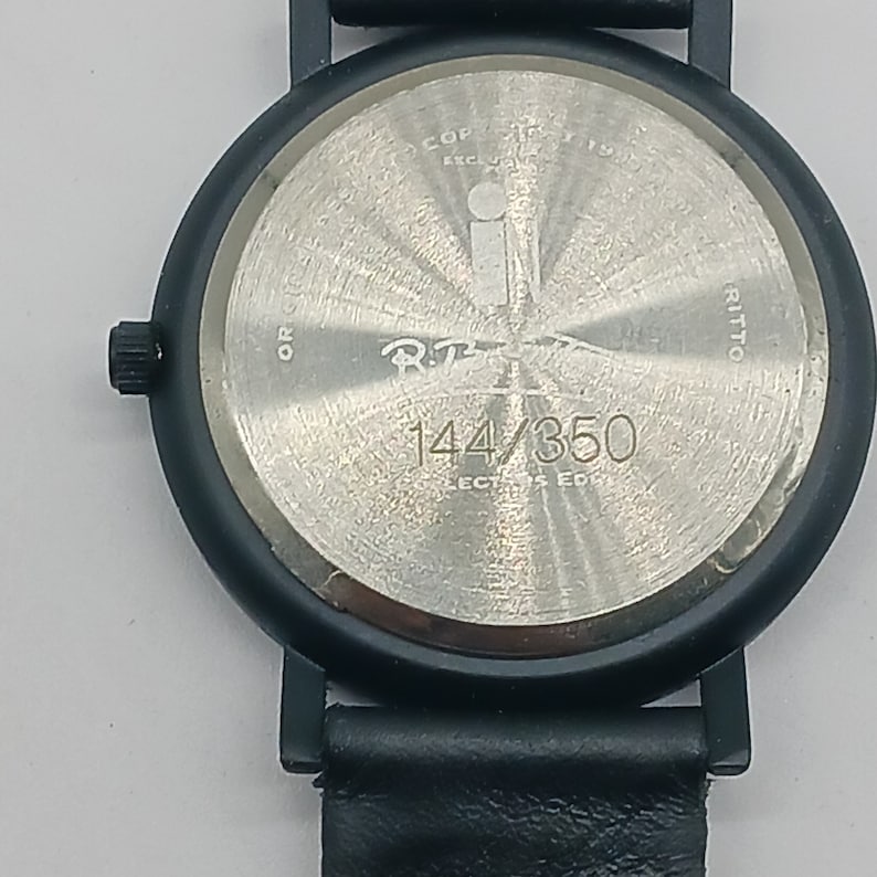 May include: Black wristwatch with a silver face and black leather band. The watch face has the text "R.T. 144/350 COLLECTORS EDITION" on it.