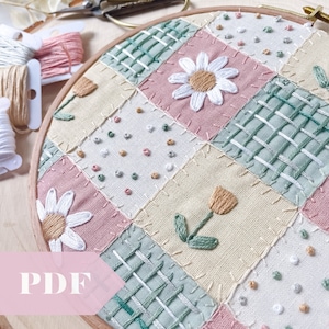 Op de afbeelding: Een ronde borduurring met een patchwork-ontwerp met verschillende bloemenmotieven, waaronder madeliefjes en tulpen, in tinten roze, groen en geel. De ring is omgeven door borduurgaren en een houten frame.