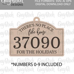 May include: A tan-coloured zip code ornament with the text "THERE'S NO PLACE like home" and "37090 FOR THE HOLIDAYS". The ornament includes the text "*NUMBERS 0-9 INCLUDED". The design is from Grey Birch Designs.