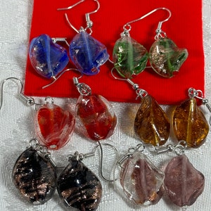 May include: Assortment of ten pairs of dangle earrings with silver hooks. The earrings feature various colors and patterns of glass beads, including blue, green, red, gold, brown, and clear.