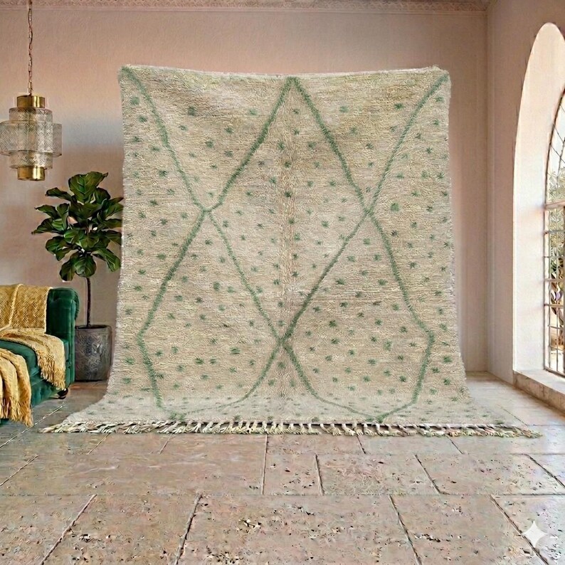 May include: A large, rectangular rug with a cream-colored background and a geometric design in light green. The design features diamond shapes and small dots. The rug has a fringe along the bottom edge, adding texture and detail to the floor covering.