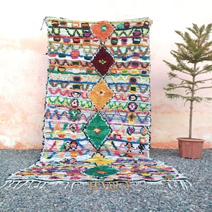 Eco-friendly Moroccan carpet with diamond motifs in green, yellow, orange, and blue.