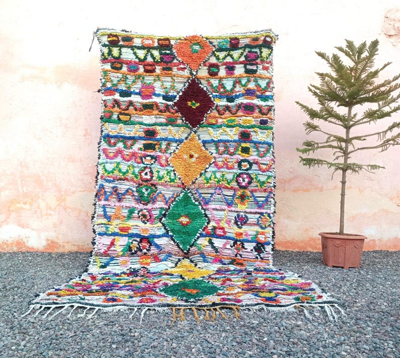 Eco-friendly Moroccan carpet with diamond motifs in green, yellow, orange, and blue.