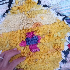 Eco-friendly Moroccan carpet with diamond motifs in green, yellow, orange, and blue.