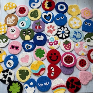 May include: A collection of colorful, round, hand-stitched wool rug ornaments with various designs, including hearts, flowers, animals, and geometric patterns.
