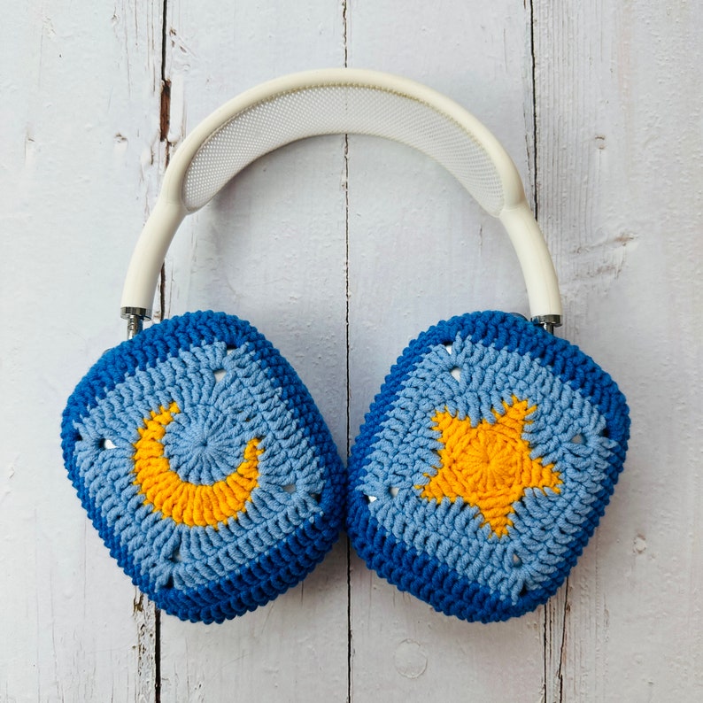 May include: Blue and yellow crocheted headphones with a crescent moon and star design. The headphones are made of soft yarn and are perfect for listening to music or podcasts.