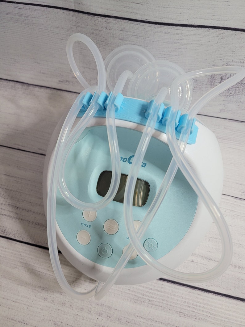 K&ouml;nnte beinhalten: Eine blaue und wei&szlig;e elektrische Milchpumpe mit digitalem Display und klaren Schl&auml;uchen. Die Pumpe hat einen Zyklusknopf, einen Ein- und Ausschalter und einen Knopf zum Einstellen des Sauggrads.