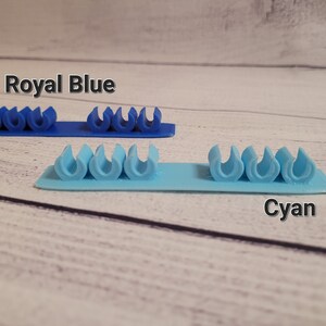 K&ouml;nnte beinhalten: Zwei Reihen Kabelorganizer, eine in Royalblau und eine in Cyan. Jede Reihe hat f&uuml;nf Kabelorganizer.