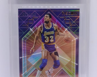 May include: A graded trading card of Magic Johnson, a basketball player for the Los Angeles Lakers. The card is a 2021 Recon Holo Bronze card, numbered 1/299. The card is in a protective case with a mint condition rating of 9.
