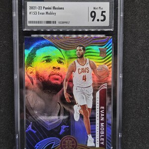 Puede incluir: Una tarjeta coleccionable Panini Illusions 2021-22, #153, de Evan Mobley, con una calificaci&oacute;n Mint Plus 9.5. La tarjeta presenta un dise&ntilde;o hologr&aacute;fico con im&aacute;genes del jugador de los Cavaliers de Cleveland. La tarjeta est&aacute; dentro de un soporte protector.