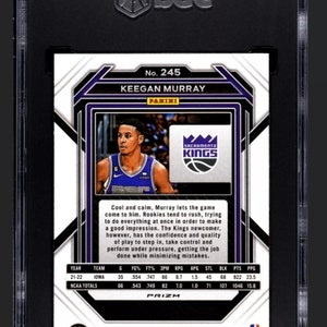 May include: A basketball trading card featuring Keegan Murray, a player for the Sacramento Kings. The card is a Prizm card from the 2022-23 Panini Prizm Basketball set. The card features a photo of Murray in his Kings uniform, along with his stats and a brief description of his playing style.