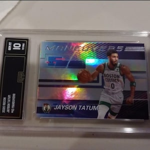 Pode incluir: Um cart&atilde;o de troca classificado com um jogador de basquete vestindo um uniforme verde e branco. O cart&atilde;o &eacute; um cart&atilde;o Jayson Tatum "Mio Maneuvers" Recon 2020. O cart&atilde;o &eacute; classificado com um 10.