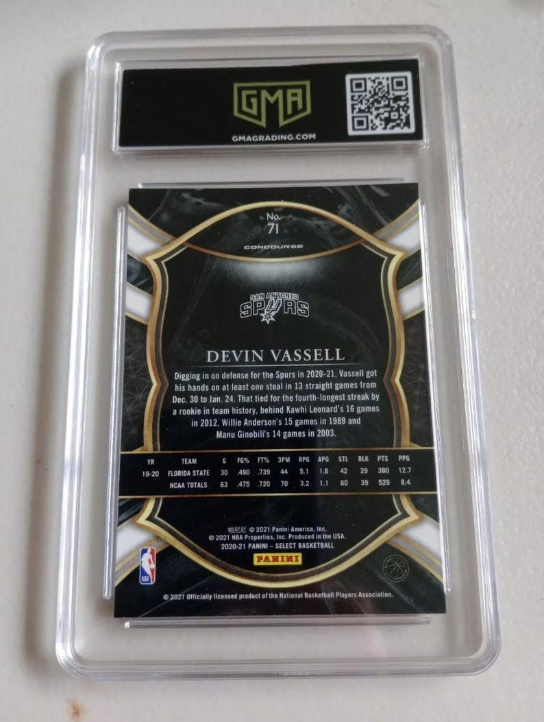Puede incluir: Una tarjeta de intercambio con Devin Vassell, un jugador de baloncesto de los San Antonio Spurs. La tarjeta es dorada y negra con una foto de Vassell con su uniforme. El n&uacute;mero de la tarjeta es 71. La tarjeta incluye estad&iacute;sticas de la carrera de Vassell.