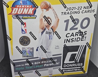 Puede incluir: Una caja amarilla y negra con las palabras "NBA Dunk" y "Donruss Basketball" en ella. La caja presenta a un jugador de baloncesto con una camiseta blanca con el número 77. La caja dice "2021-22 NBA Trading Cards" y "120 Cartas dentro!"