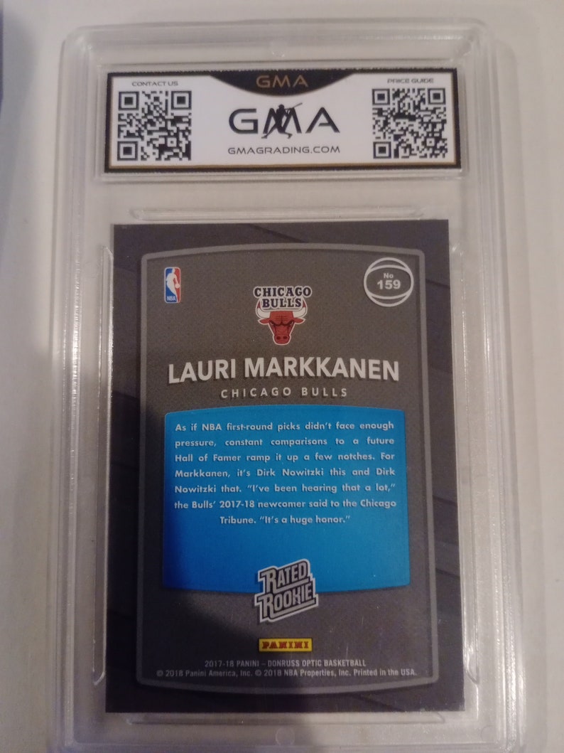 May include: A blue and white basketball card featuring Lauri Markkanen, a player for the Chicago Bulls. The card is from the 2017-18 Panini Donruss Optic Basketball series and has a Rated Rookie designation. The card number is 159.