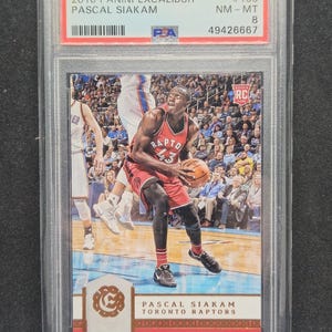 Op de afbeelding: Een 2016 Panini Excalibur trading card met Pascal Siakam van de Toronto Raptors. De kaart is beoordeeld als NM-MT 8 door PSA en bevat de tekst "Raptors 43". De kaart zit in een beschermende houder.
