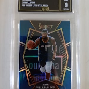May include: A blue and gold basketball trading card featuring Zion Williamson of the New Orleans Pelicans. The card is graded a 9 by GMA and is a 2021 Select Premier Level Retail Prizm.
