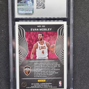 Puede incluir: Tarjeta de baloncesto de Evan Mobley con la camiseta de los Cavaliers de Cleveland, en un soporte protector. La tarjeta detalla las estad&iacute;sticas de la temporada de novato de Mobley, incluyendo un doble-doble.