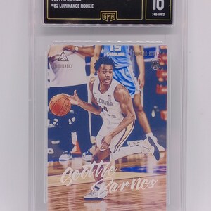 Op de afbeelding: Een gegradeerde trading card met een basketballer in een wit en gouden uniform die de bal dribbelt. De kaart is gelabeld "2021 Chronicles Draft Picks" en "Scottie Barnes #82 Luminance Rookie". De kaart is gegradeerd GEM MT 10.