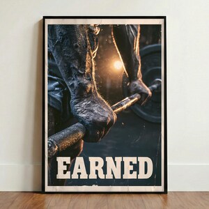 Puede incluir: Un póster vertical enmarcado que muestra un primer plano de brazos musculosos agarrando una barra de pesas de metal texturizado. La escena está tenuemente iluminada con una luz cálida al fondo. La palabra EARNED aparece en letras blancas grandes.