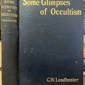 May include: A dark blue hardcover book titled "Some Glimpses of Occultism" by C.W. Leadbeater. The title and author's name are in gold lettering. The book's spine also features the title and author's name in gold.